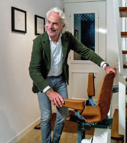 Senior souriant à côté de son monte-escalier installé dans son entrée